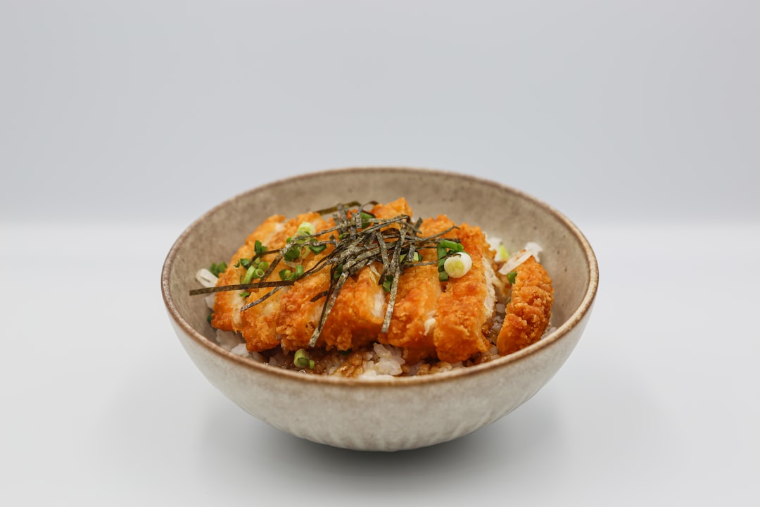 a-bowl-filled-with-rice-and-meat-covered-in-sauce-heea50zho4o